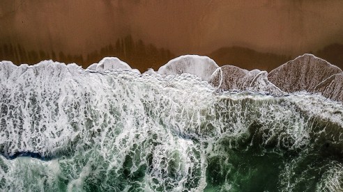 Ocean-Waves-Meet-Red-Sands-Aerial_9KL76aFT7PHN